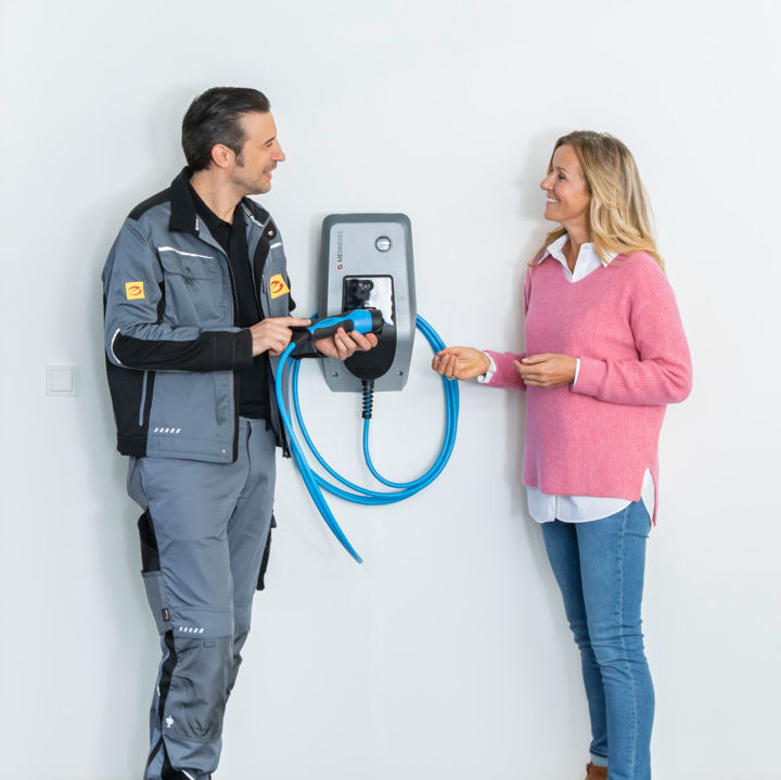 Installateur berät eine Kundin zur Handhabung einer Wallbox